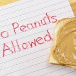 Lined primary school paper with "No Peanuts Allowed" written in red crayon warns against peanut products which are dangerous food allergens